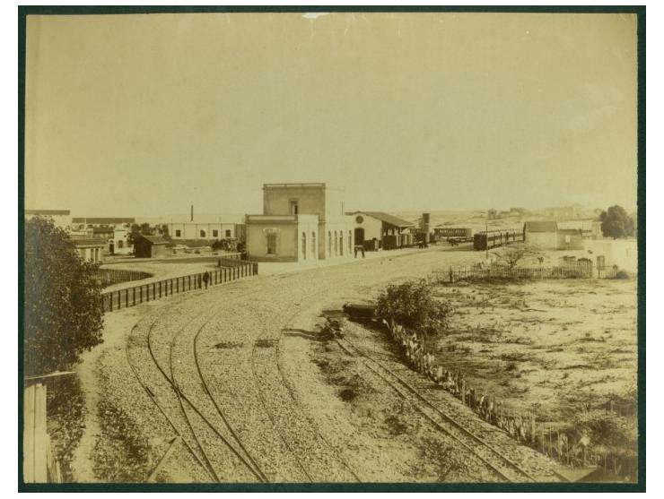 תצלום תחנת הרכבת ביפו, [שנות העשרה של המאה ה-20]. אינו חתום ואינו מתוארך.
בחזית המבנה (כיום "מתחם התחנה") נראות שתי